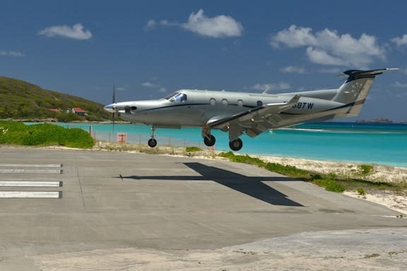 A light twin on the ramp under midday sun, its shadow hard on the concrete